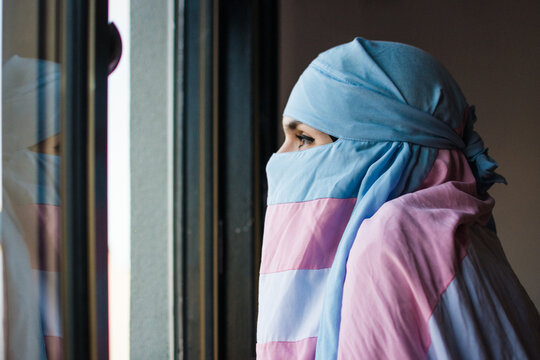 Trans muslim person looking through the window