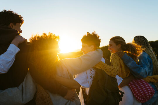 Group of diverse friends spending time together at sunset