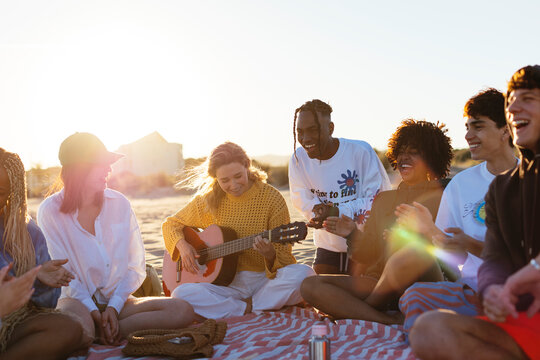 Group of friends spending time on beach at sunset
