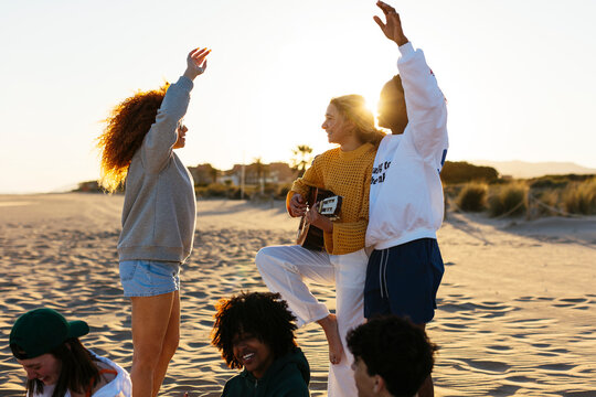 Group of friends spending time on beach at sunset