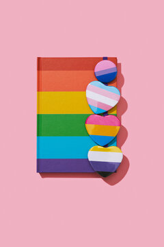 LGBTIQ pride badges on a rainbow-patterned notebook