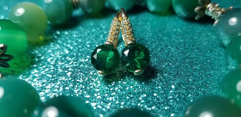 Green round beads with a matte sheen and a metal cross-shaped mount and a pair of green earrings on...