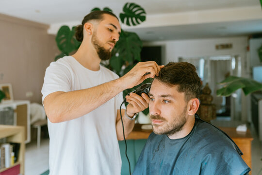 Trendy barber doing a haircut at home