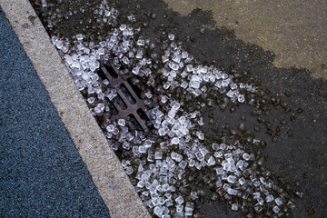 Stock image of melting ice cubes on street drain