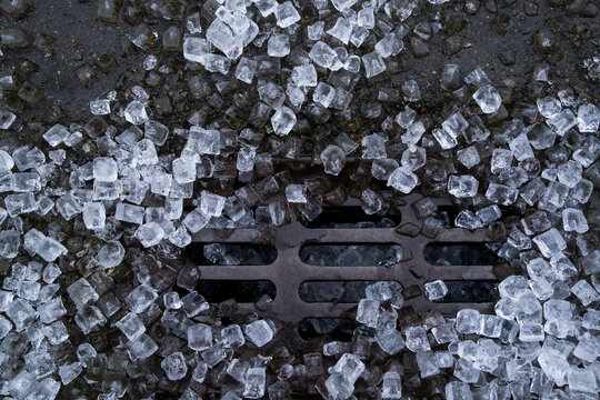 Stock image of melting ice cubes on street drain