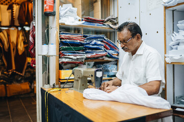 Calm Indian tailor creating shirt in workshop