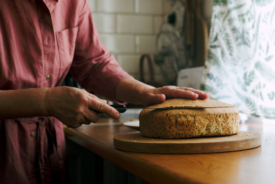 An elderly woman's hands cut sponge-cakes 