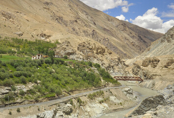 Scenic view of a small green village on dry mountain with flowing a river on the way of Padum, Zanskar, Ladakh, INDIA 
