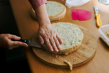 An elderly woman's hands cut sponge-cakes 