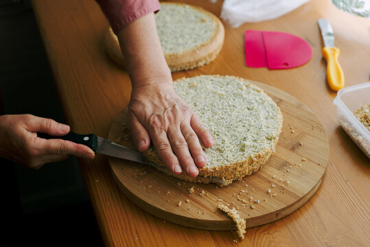 An elderly woman's hands cut sponge-cakes 