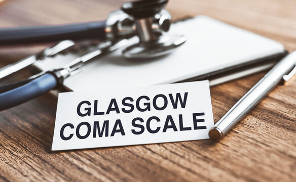 Glasgow Coma Scale - text on white sheet on a wooden background with a stethoscope. Medical concept