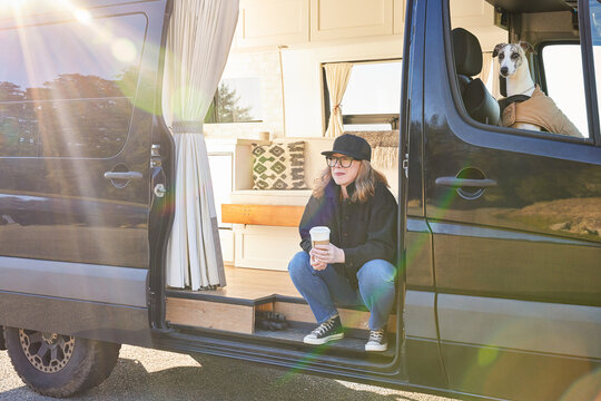 Portrait of woman camping with dog on road trip luxury camper van
