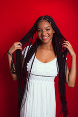 Portrait of young, beautiful woman, standing, messing with her hair braids.