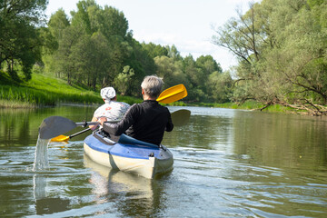Family kayak trip for seigneur and senora. An elderly married couple rowing a boat on the river, a water hike, a summer adventure. Age-related sports, mental youth and health, tourism, active old age