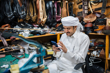 Concentrated man messaging on smartphone in workshop