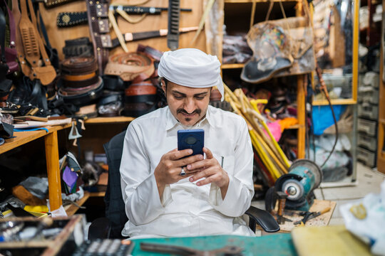 Calm man browsing smartphone in workshop