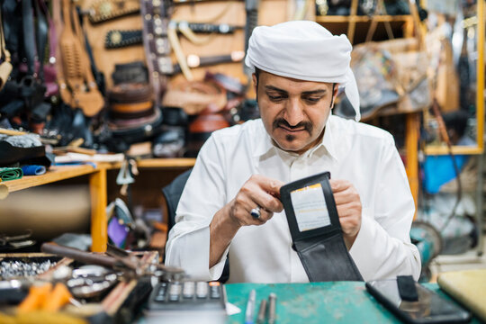 Focused Middle Eastern man making leather product