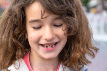 Toothless happy smile of a girl with a fallen lower milk tooth close-up. Changing teeth to molars in childhood