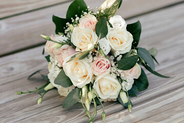 Wedding bouquet of white and pink roses on a wooden bench. Beautiful bridal bouquet of roses close-up. Traditional wedding accessory in the form of a bridal bouquet