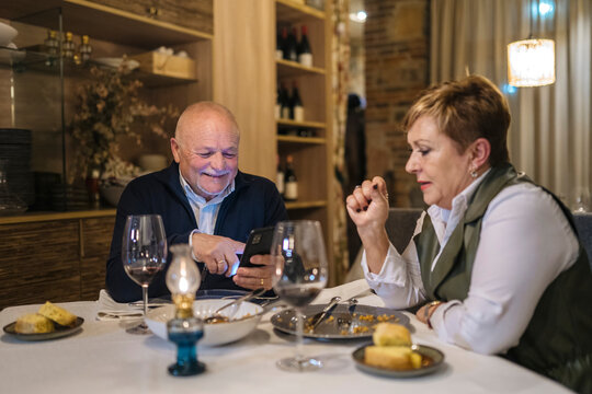 Happy senior man browsing smartphone during date