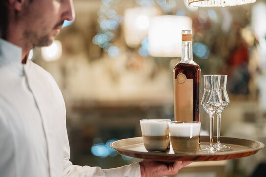 Crop waiter serving drinks in restaurant