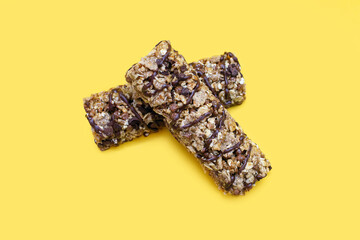 Two bars of whole oatmeal and chocolate on a yellow isolated background. Delicious healthy snack or energy replenishment. Whole grain energy bars with chocolate