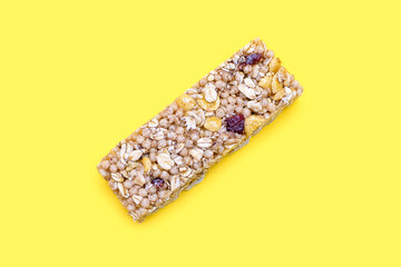Muesli bar with berries on a yellow background in the center. Healthy sweet dessert snack. Cereal muesli with nuts, oatmeal and berries on a yellow background. Delicious and healthy dessert