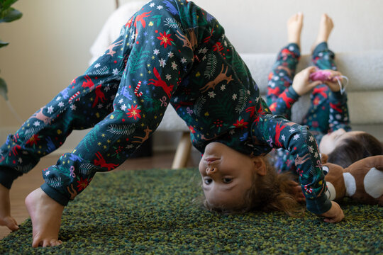 girl in pajamas stands on her head on the carpet
