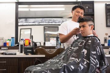 Latin teenager getting a haircut in a barbershop