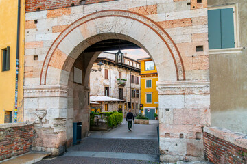 Fototapeta na wymiar Verona, Italy - September 28 2022: A arched entry from the Ponte Sisto bridge into the medieval old town of Verona, Italy.