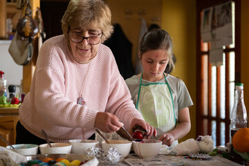 Grandma and grandchildren painting eggs for Easter. Family activity.