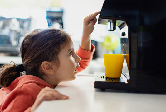 Cute kid pouring fresh water from filter machine
