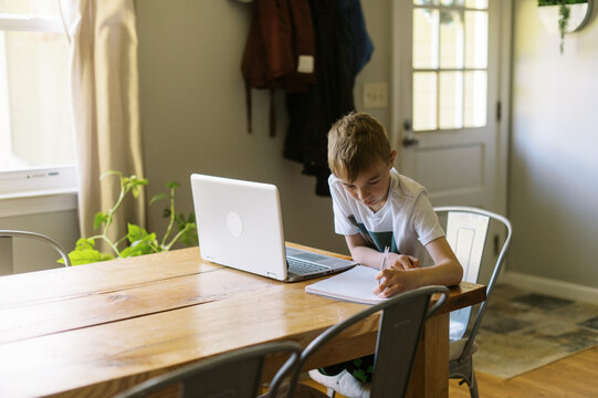 little boy doing remote school at home and writing