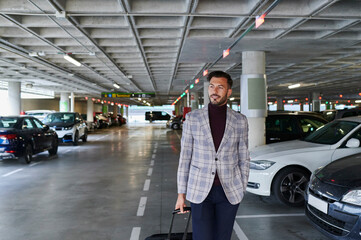 Man walking with luggage through an airport parking lot