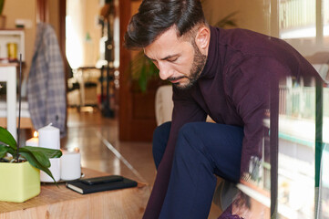 Young man tying up his shoes at home