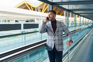 Man talking on the phone on an airport moving walkway