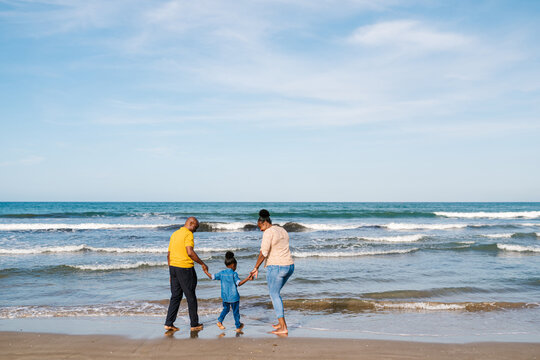 Anonymous family standing on shore of sea
