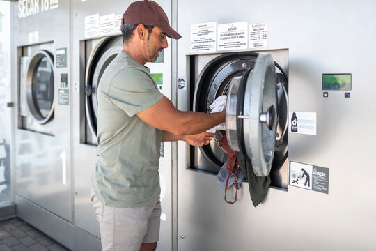young man doing laundry in a city laundry