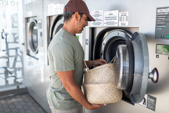 young man doing laundry in a city laundry