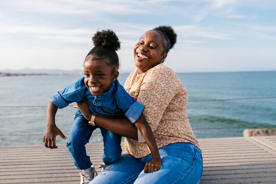 Black mother holding child playing on embankment