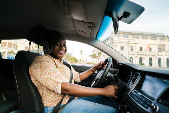 Happy black woman starting car and smiling at camera