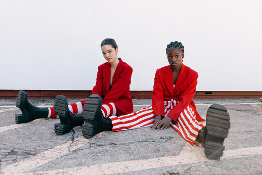 Trendy diverse models sitting on ground on street