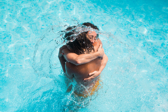 Women hug standing in pool with water splash