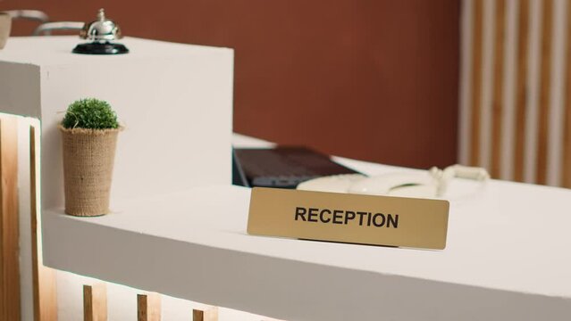 Close up of elegant modern stylish hospitality industry lounge hotel lobby check in desk. Empty welcoming resort lobby reception counter with concierge bell next to mini plant