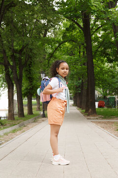 Adorable schoolkid standing on alley in city park