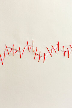 Mend it, red cotton thread joining ripped paper