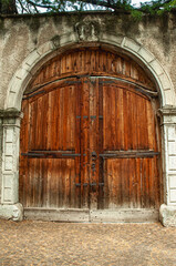   Front view, medium distance of, a pair of brown, wood, arched, gated doors, entry to walled city of, Fai della Panatella