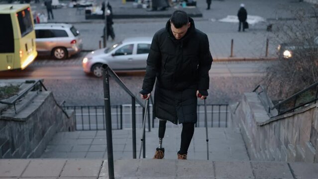 Prosthetic support, Limb difference, Climbing acceptance. Man who is disabled and has prosthetic leg climbs stairs on street in city.