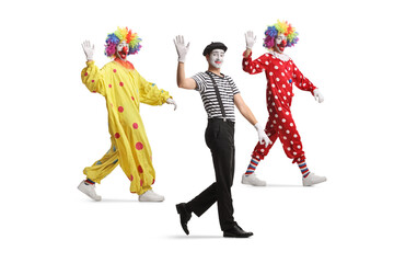 Full length shot of two clowns and a mime walking and waving