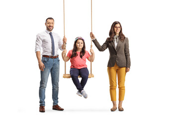 Obraz premium Girl sitting on a swing and her parents standing by her side